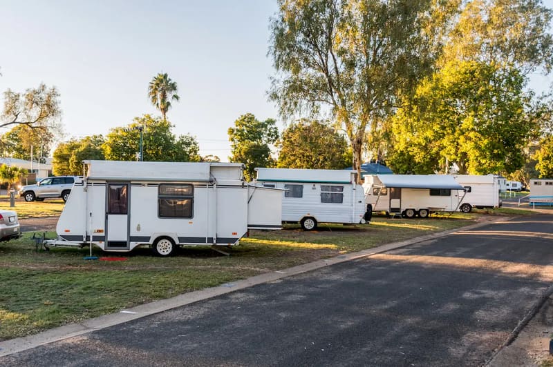 Caravans parked on grassed sites along a sealed road in a caravan park